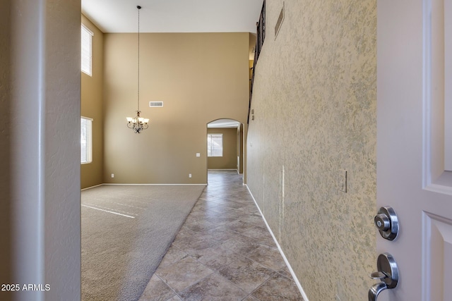 entrance foyer with a wealth of natural light, a towering ceiling, and a notable chandelier