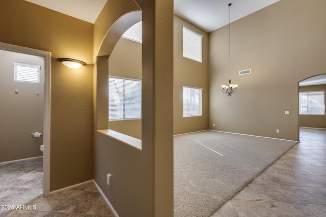 interior space with light carpet, a chandelier, and a towering ceiling