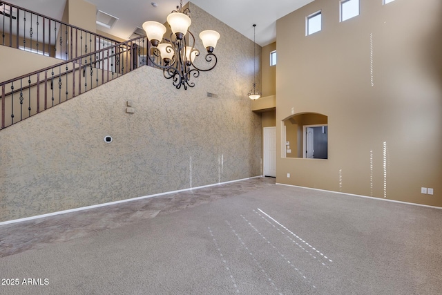 unfurnished living room with carpet flooring, a towering ceiling, and a notable chandelier