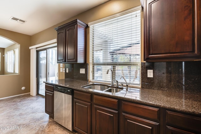 kitchen with tasteful backsplash, dark stone countertops, dishwasher, dark brown cabinetry, and sink