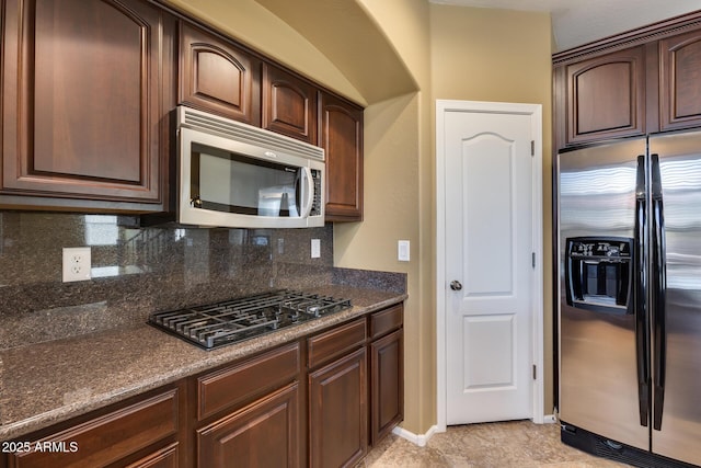 kitchen with stainless steel appliances, decorative backsplash, and dark brown cabinets