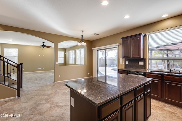 kitchen featuring ceiling fan with notable chandelier, pendant lighting, dishwasher, a kitchen island, and sink