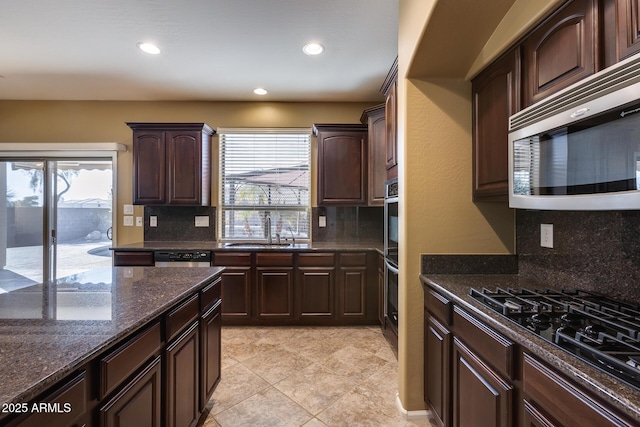 kitchen with a healthy amount of sunlight, appliances with stainless steel finishes, sink, and dark stone counters