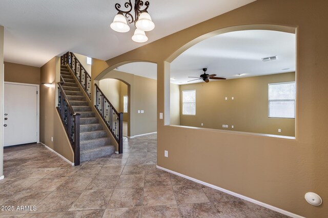 foyer entrance with ceiling fan with notable chandelier