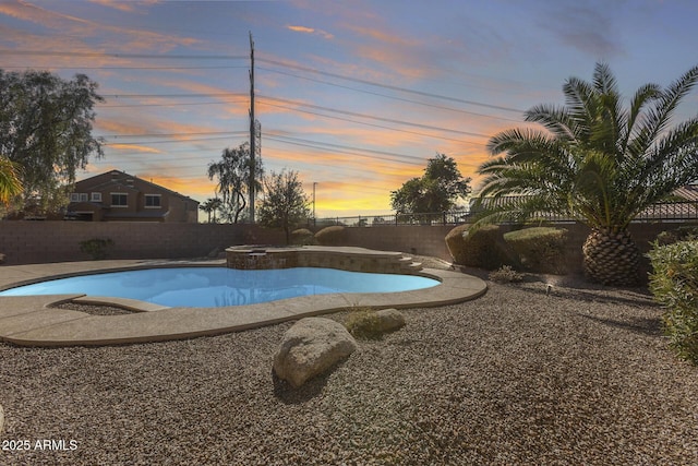 pool at dusk with an in ground hot tub