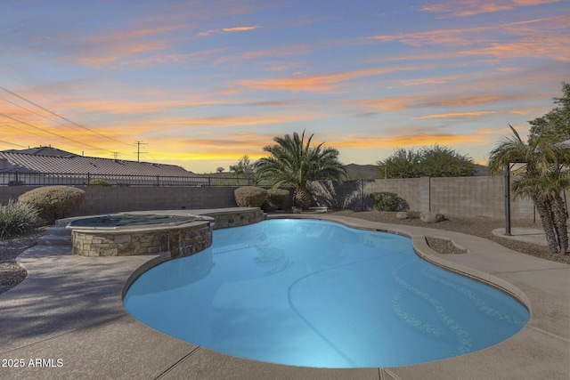 pool at dusk with an in ground hot tub