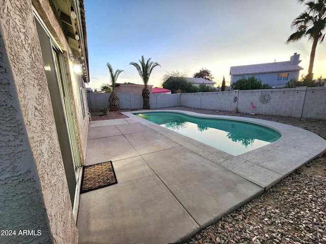 pool at dusk featuring a patio area