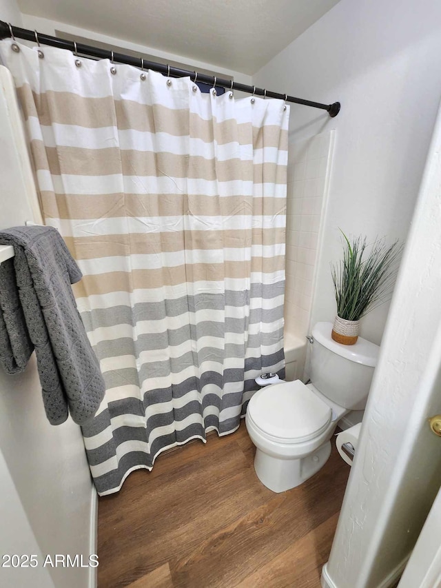 bathroom with curtained shower, wood-type flooring, and toilet