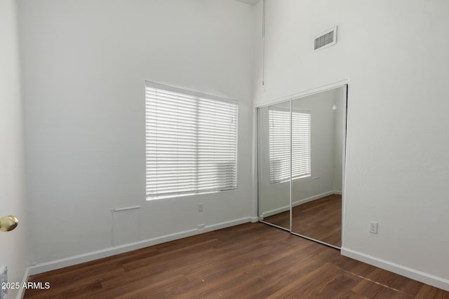 unfurnished bedroom featuring dark hardwood / wood-style floors and a closet