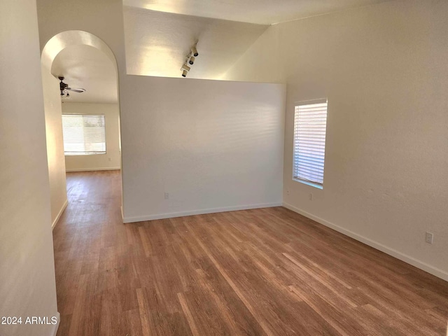 unfurnished room with hardwood / wood-style flooring, ceiling fan, track lighting, and vaulted ceiling