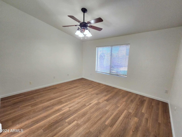 empty room featuring dark hardwood / wood-style floors, vaulted ceiling, and ceiling fan