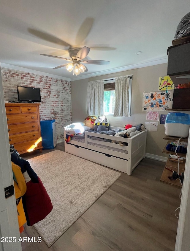 bedroom featuring ceiling fan, brick wall, ornamental molding, and dark hardwood / wood-style flooring