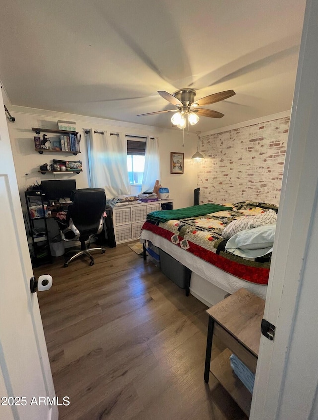 bedroom with ceiling fan, hardwood / wood-style floors, and brick wall