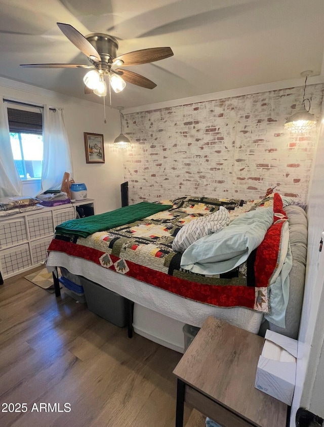 bedroom with ornamental molding, ceiling fan, brick wall, and hardwood / wood-style floors