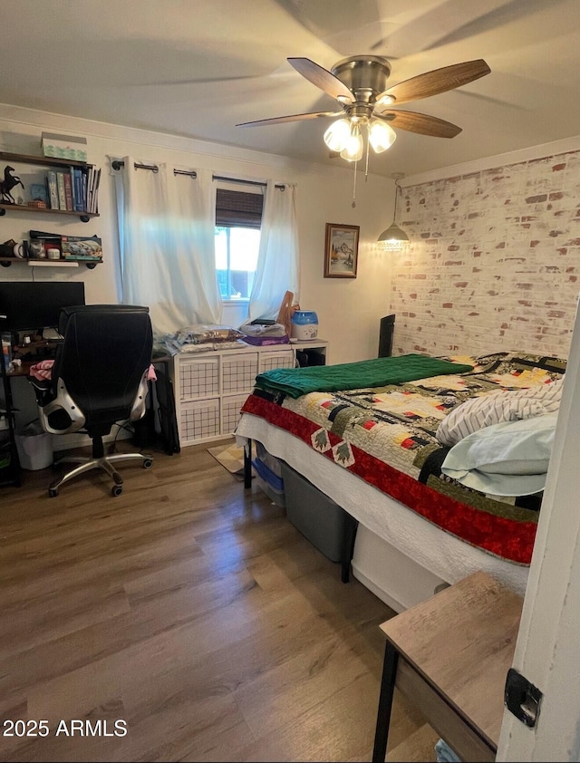 bedroom featuring ceiling fan, brick wall, and hardwood / wood-style flooring