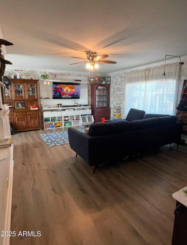 living room featuring wood-type flooring, brick wall, and ceiling fan