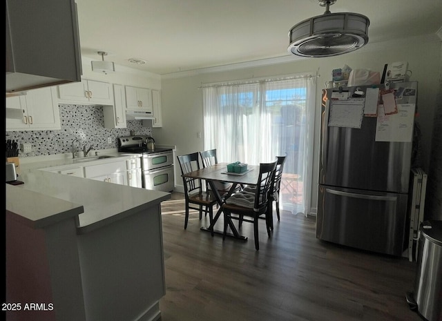 kitchen with white cabinets, stainless steel appliances, sink, backsplash, and kitchen peninsula