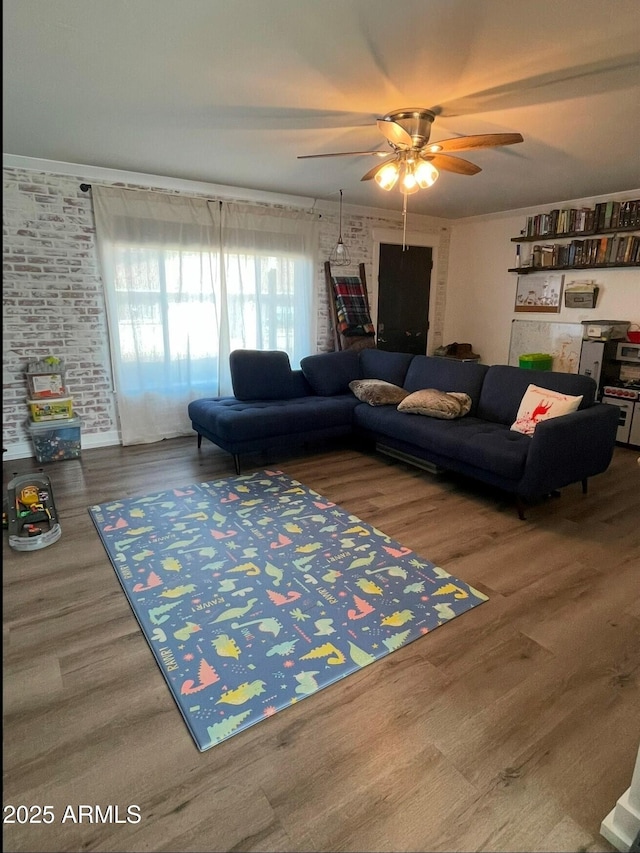 living room featuring hardwood / wood-style flooring, brick wall, ceiling fan, and crown molding