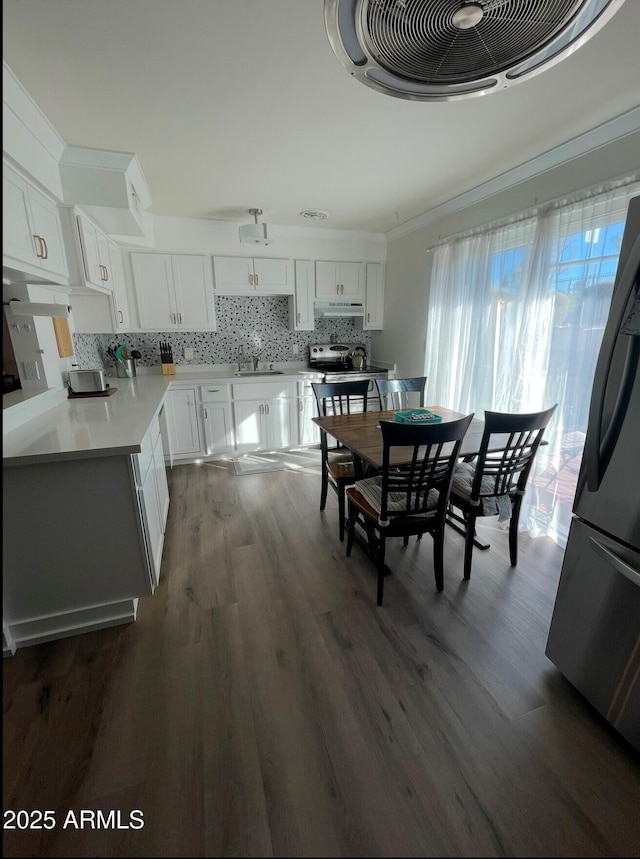 dining area featuring sink, crown molding, and dark wood-type flooring