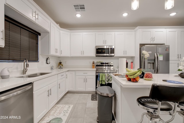 kitchen with white cabinets, light tile patterned flooring, pendant lighting, sink, and stainless steel appliances