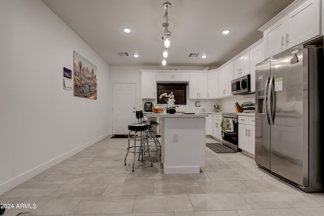 kitchen featuring appliances with stainless steel finishes, a kitchen island, a breakfast bar, and white cabinetry