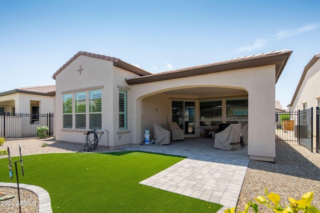 rear view of house with a patio area, fence, a lawn, and stucco siding