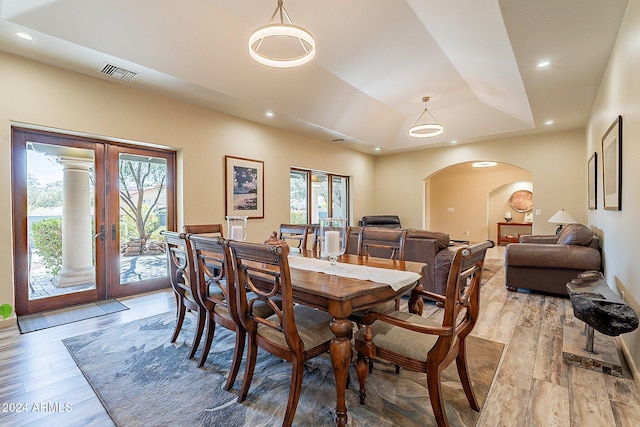 dining space featuring french doors, a tray ceiling, a wealth of natural light, and light wood-type flooring