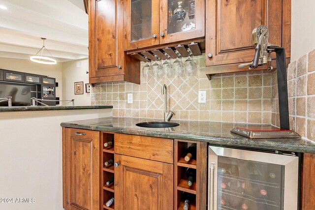 kitchen with beverage cooler, backsplash, dark stone counters, sink, and decorative light fixtures