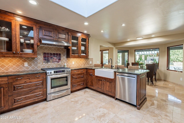 kitchen featuring sink, appliances with stainless steel finishes, kitchen peninsula, and backsplash