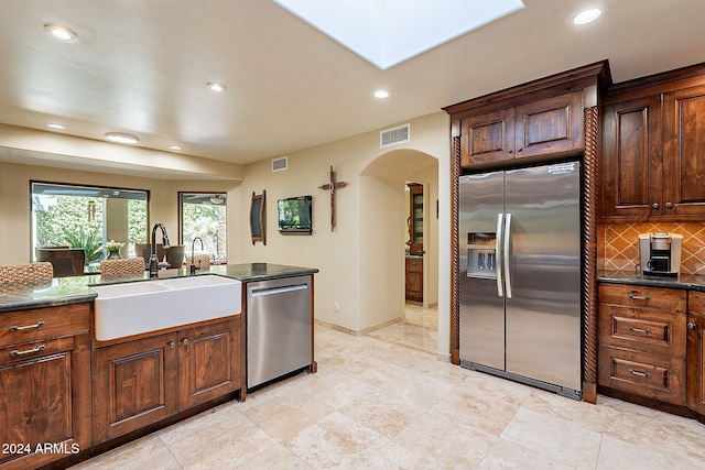 kitchen with dark stone countertops, appliances with stainless steel finishes, sink, and decorative backsplash