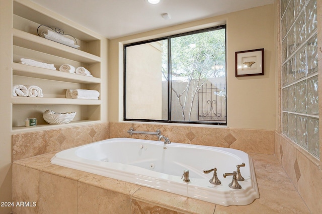 bathroom with built in shelves and tiled tub