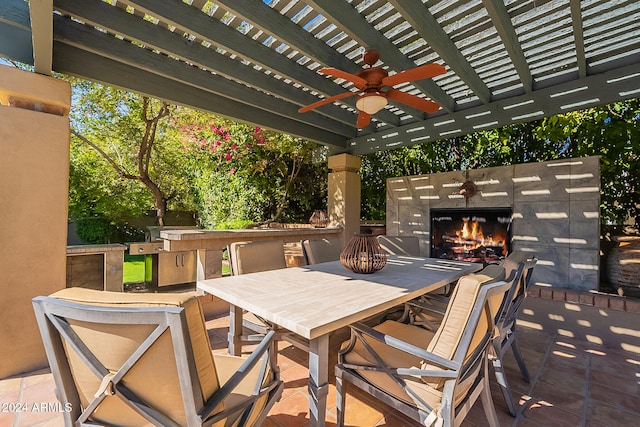 view of patio / terrace with a pergola, ceiling fan, exterior fireplace, and exterior kitchen