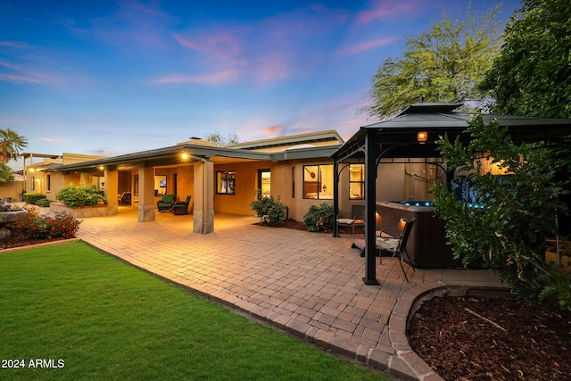 back house at dusk featuring a gazebo, a yard, and a patio area