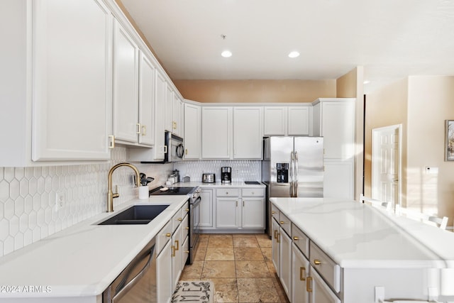 kitchen with white cabinetry, appliances with stainless steel finishes, sink, and light stone counters