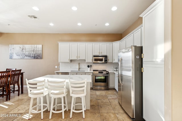 kitchen featuring tasteful backsplash, white cabinetry, sink, a center island, and stainless steel appliances