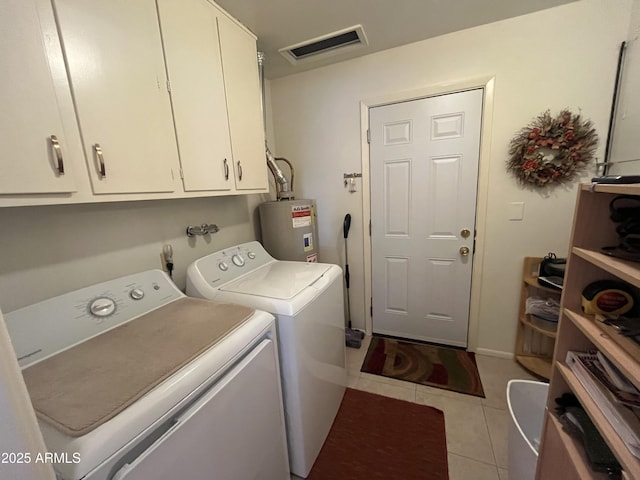 washroom with cabinets, electric water heater, washer and dryer, and light tile patterned floors