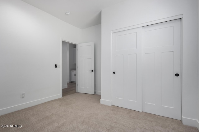 unfurnished bedroom with a closet and light colored carpet