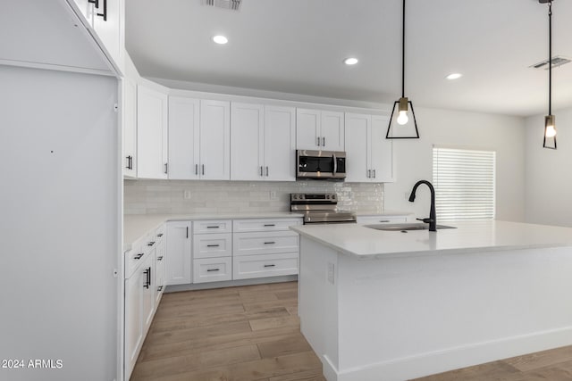 kitchen with white cabinets, decorative light fixtures, appliances with stainless steel finishes, and sink