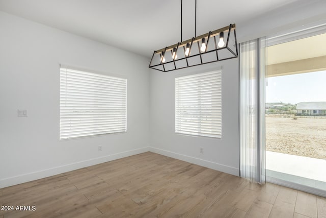 unfurnished dining area featuring light wood-type flooring and a notable chandelier