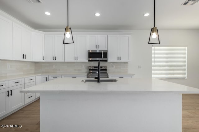 kitchen featuring hanging light fixtures, white cabinets, appliances with stainless steel finishes, and sink