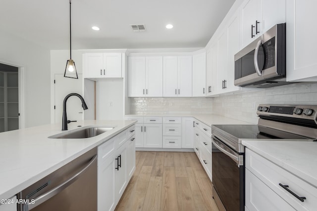 kitchen featuring light stone countertops, stainless steel appliances, light wood-type flooring, and sink