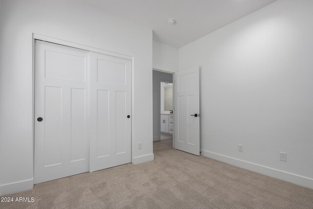 unfurnished bedroom with a closet and light colored carpet