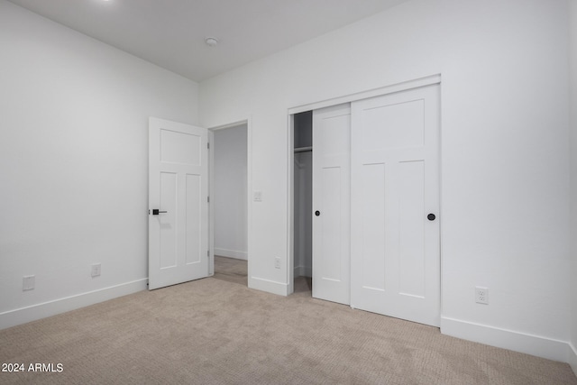 unfurnished bedroom featuring a closet and light colored carpet