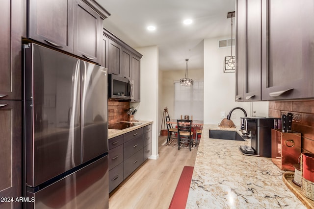 kitchen with sink, light hardwood / wood-style flooring, decorative backsplash, appliances with stainless steel finishes, and decorative light fixtures