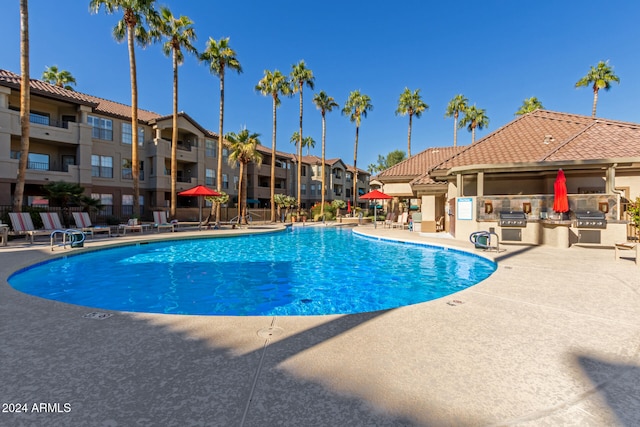 view of swimming pool featuring an outdoor kitchen, grilling area, and a patio area