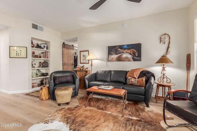 14950 W Mountain View Blvd Unit 4205, Surprise, AZ 85374 - living area featuring a barn door, wood finished floors, a ceiling fan, built in shelves, and baseboards