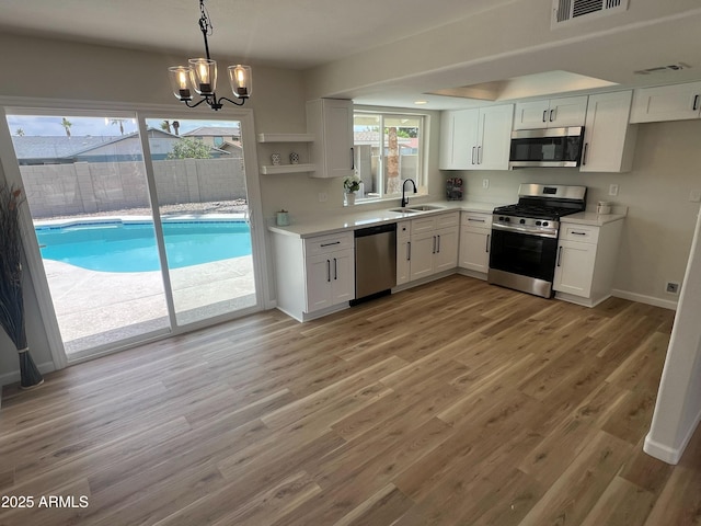 1545 W Marco Polo Rd, Phoenix, AZ 85027 - kitchen with stainless steel appliances, a sink, white cabinets, and a chandelier