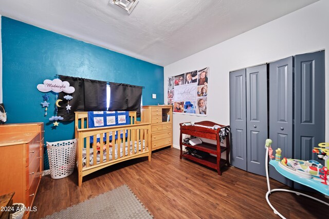 bedroom featuring a crib, a closet, and wood-type flooring