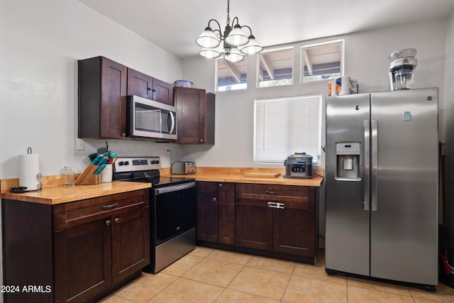 kitchen featuring light tile patterned flooring, stainless steel appliances, wood counters, and a chandelier