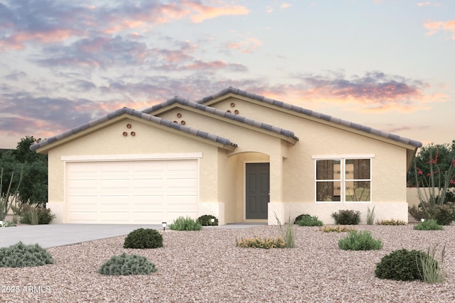 mediterranean / spanish home with a garage, driveway, a tile roof, and stucco siding